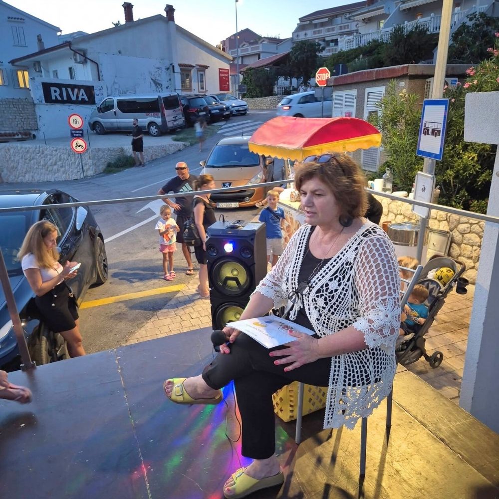 Gostovanje u Metajni – Maja Cimbal čita djeci na ljetnoj pozornici na rivi, uz priču, ples i pjesmu