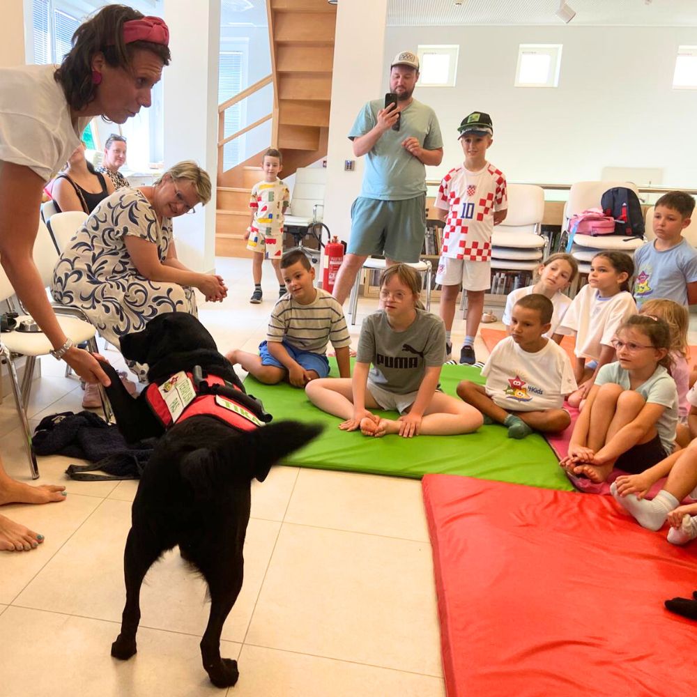 Novalja4Kids 2025 u Gradskoj knjižnici Novalja: Maja Cimbal priča djeci; Tira, terapijski pas, sudjeluje s voditeljicom Maide Arslanagić.
