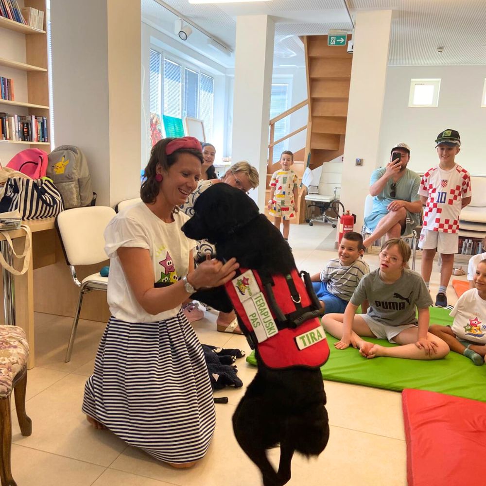 Novalja4Kids 2025 u Gradskoj knjižnici Novalja: Maja Cimbal priča djeci; Tira, terapijski pas, sudjeluje s voditeljicom Maide Arslanagić.