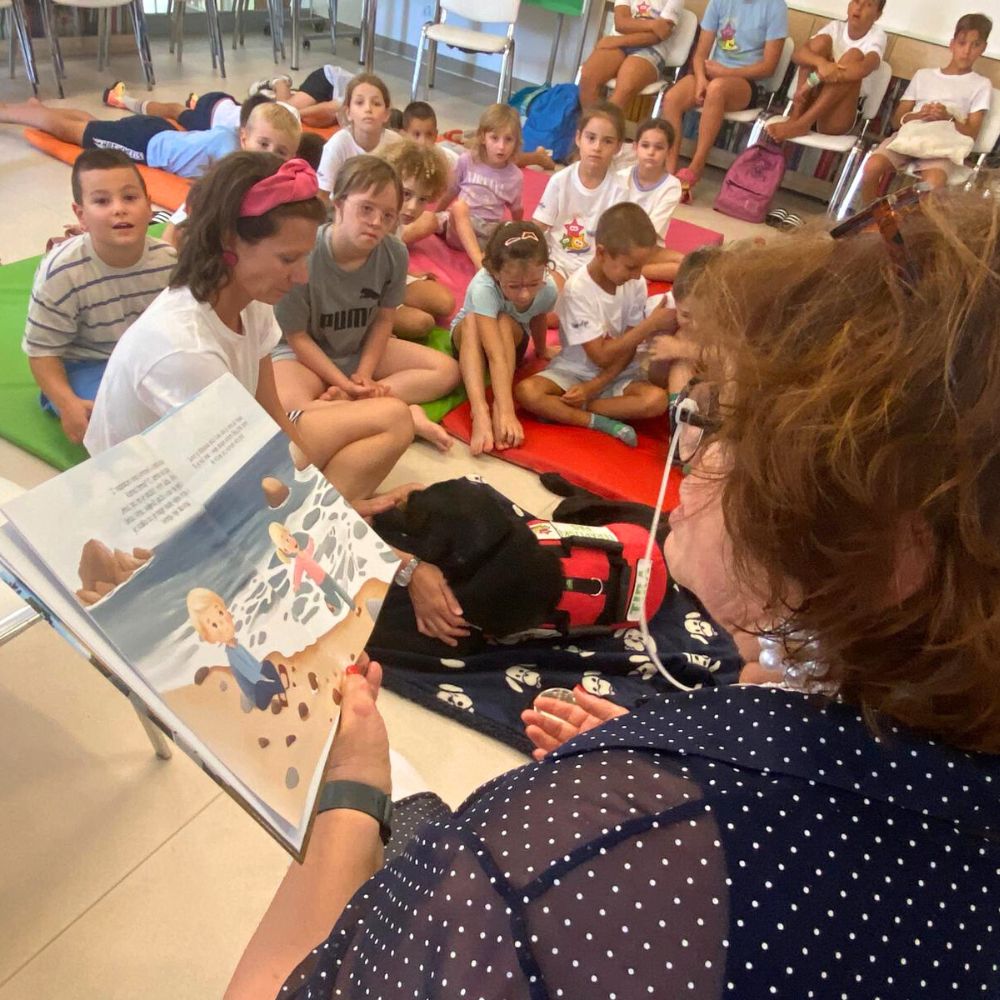 Novalja4Kids 2025 u Gradskoj knjižnici Novalja: Maja Cimbal priča djeci; Tira, terapijski pas, sudjeluje s voditeljicom Maide Arslanagić.