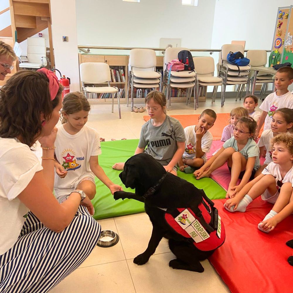 Novalja4Kids 2025 u Gradskoj knjižnici Novalja: Maja Cimbal priča djeci; Tira, terapijski pas, sudjeluje s voditeljicom Maide Arslanagić.