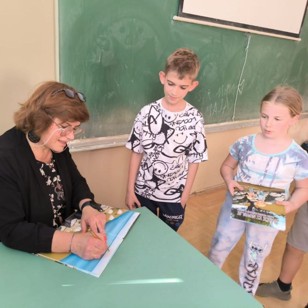 Radionica s učenicima OŠ A. G. Matoša u Novalji: Maja Cimbal čita „Priče iz Novalje – David otkriva legendu o Caskoj“ i razgovara s djecom.